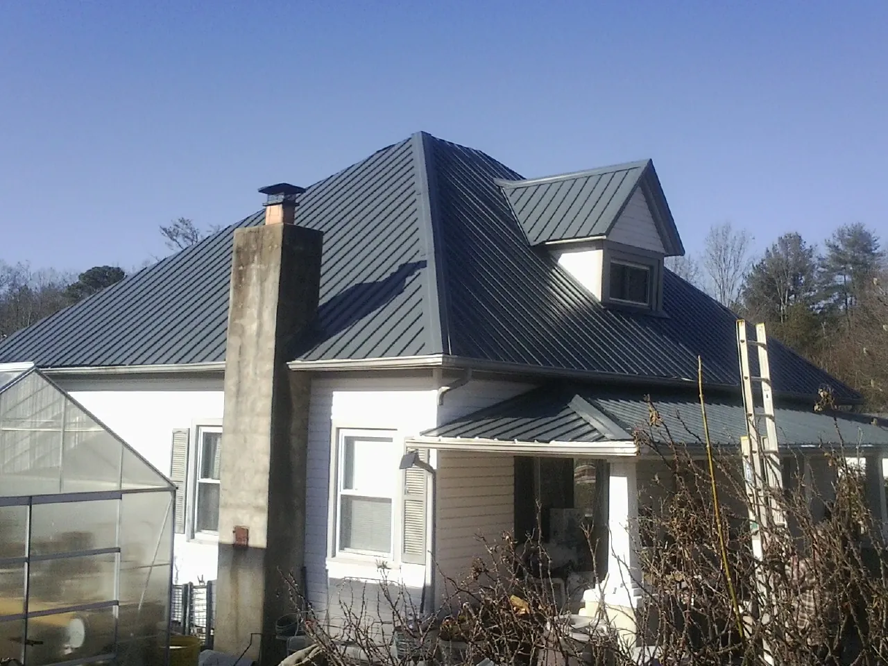 Dark blue standing seam metal roof on a white farmhouse with dormer — Slate & Tile Roof Repair by Roofing Brothers in Haltom City
