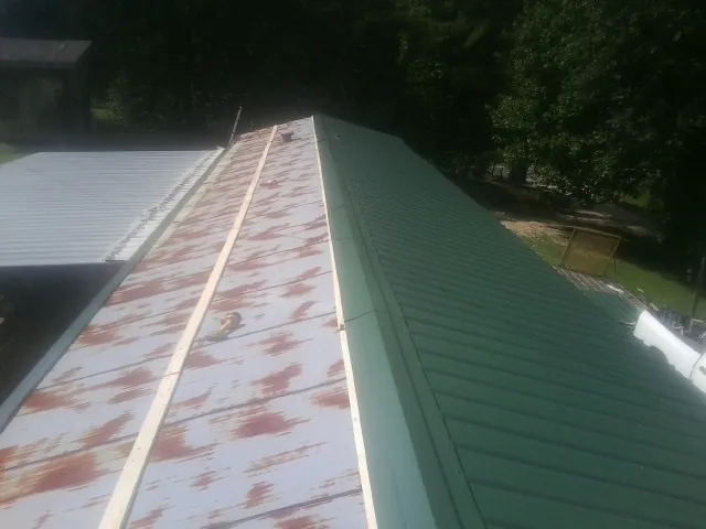 Old rusted panels beside newly installed green metal roofing — Wind Damage Roof Repair by Roofing Brothers in Haltom City