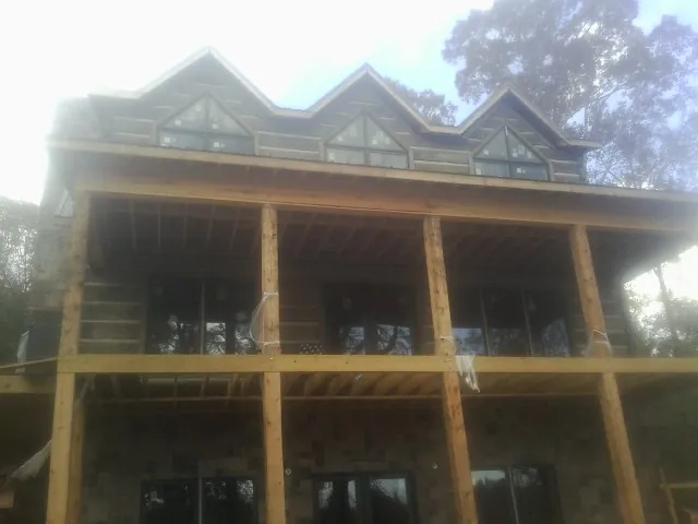 Dormers and porch framing on a large log home under construction — Roof Coating work by our crew in Haltom City