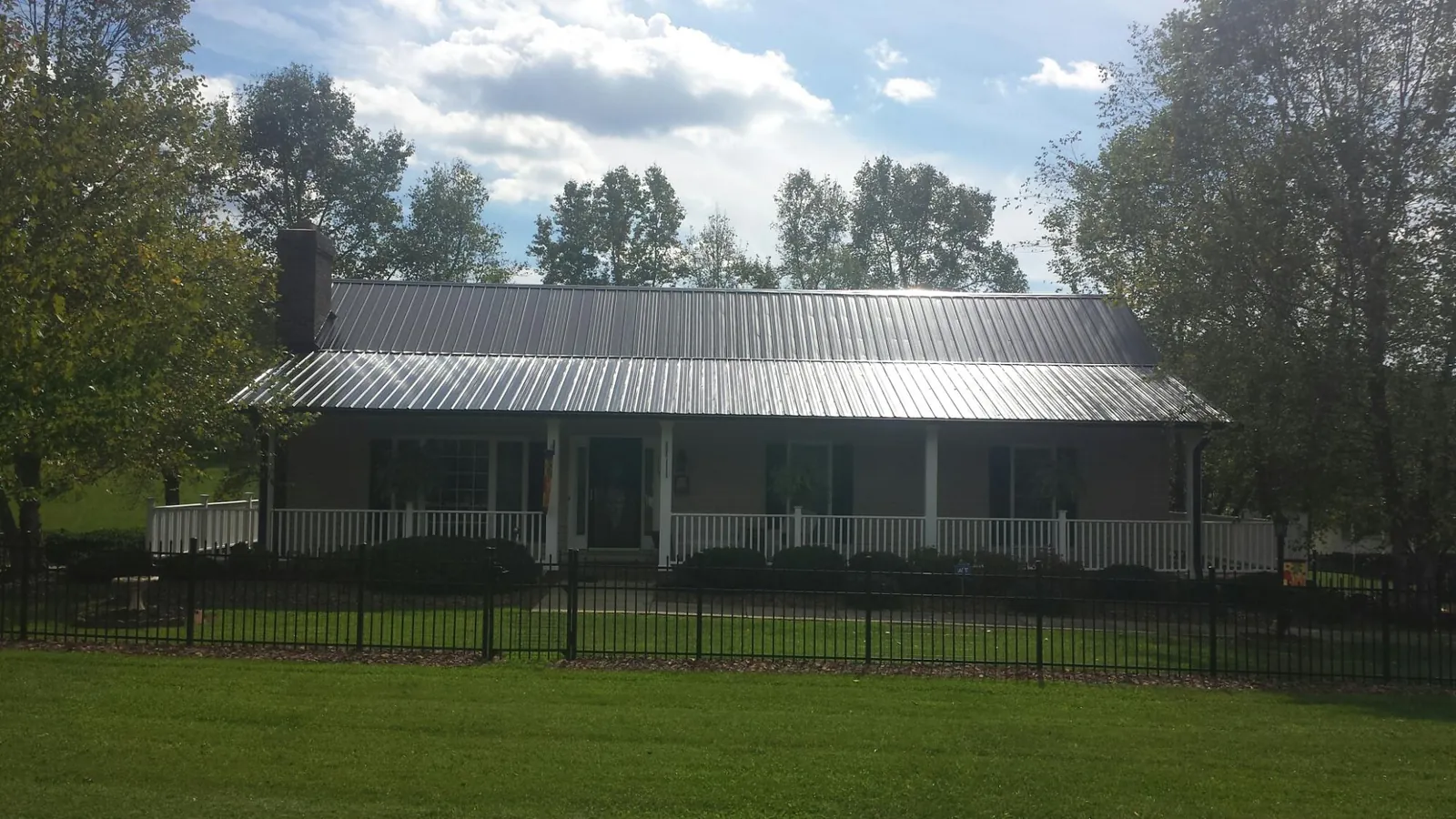 Gray metal roof on a brick ranch with a full width front porch — Gutter Guard Installation work by our crew in Haltom City