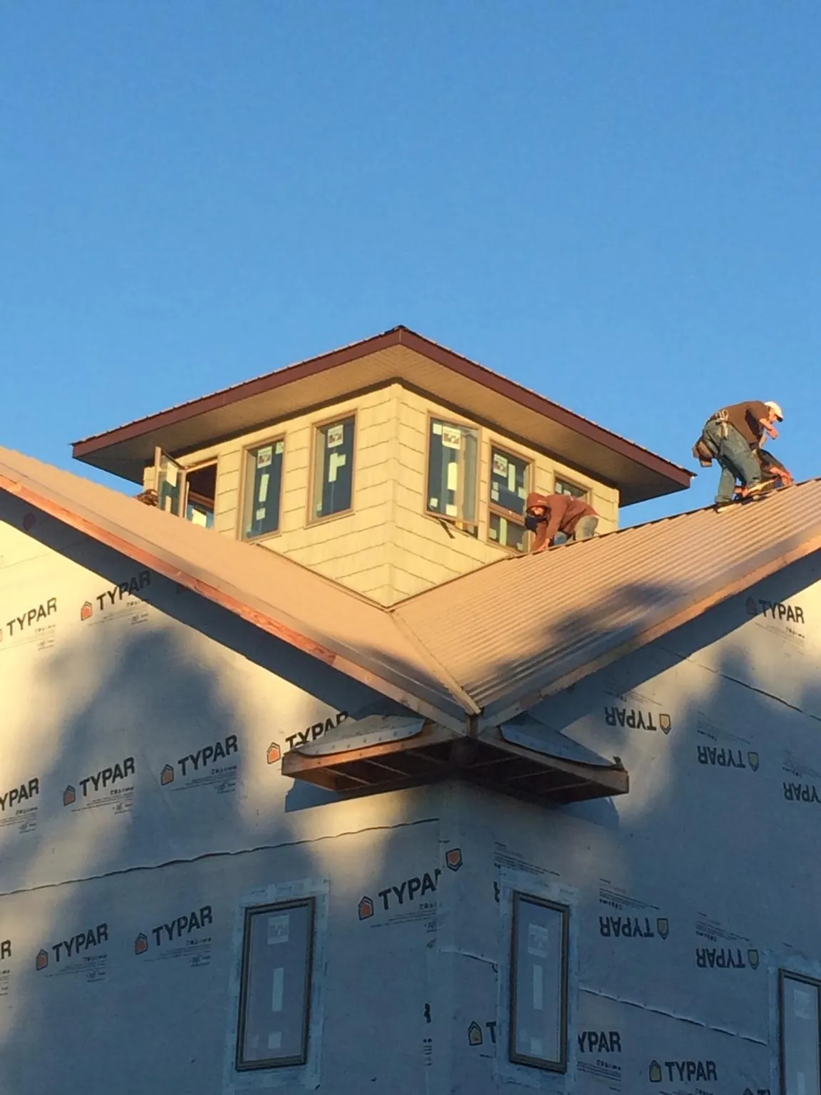 Roofers working around a rooftop cupola on a new metal roof at sunset — Roof Waterproofing in Haltom City by Roofing Brothers